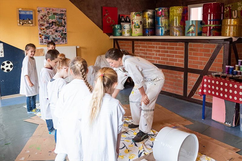 Künstlerin Tila bemalt mit Kindern Metalltonnen Künstlerin Tila bemalt mit Kindern Metalltonnen